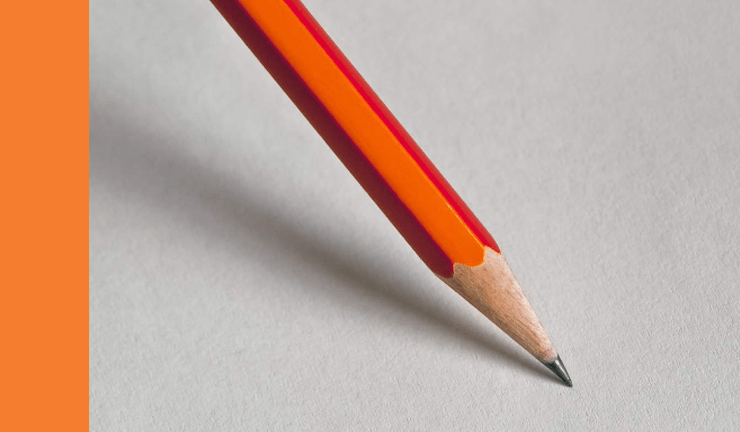 orange pencil leaning on writing surface